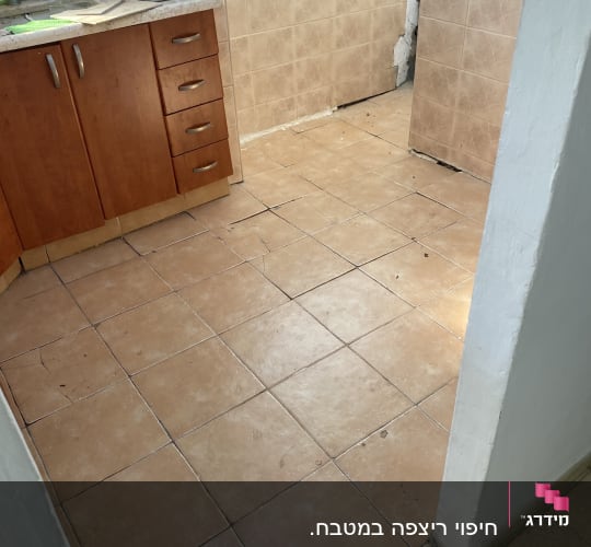 מטבח עם אריחים שבורים ופינת קיר מתקלפת